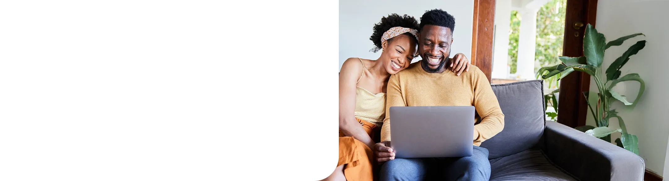 young couple using a laptop on their living room sofa